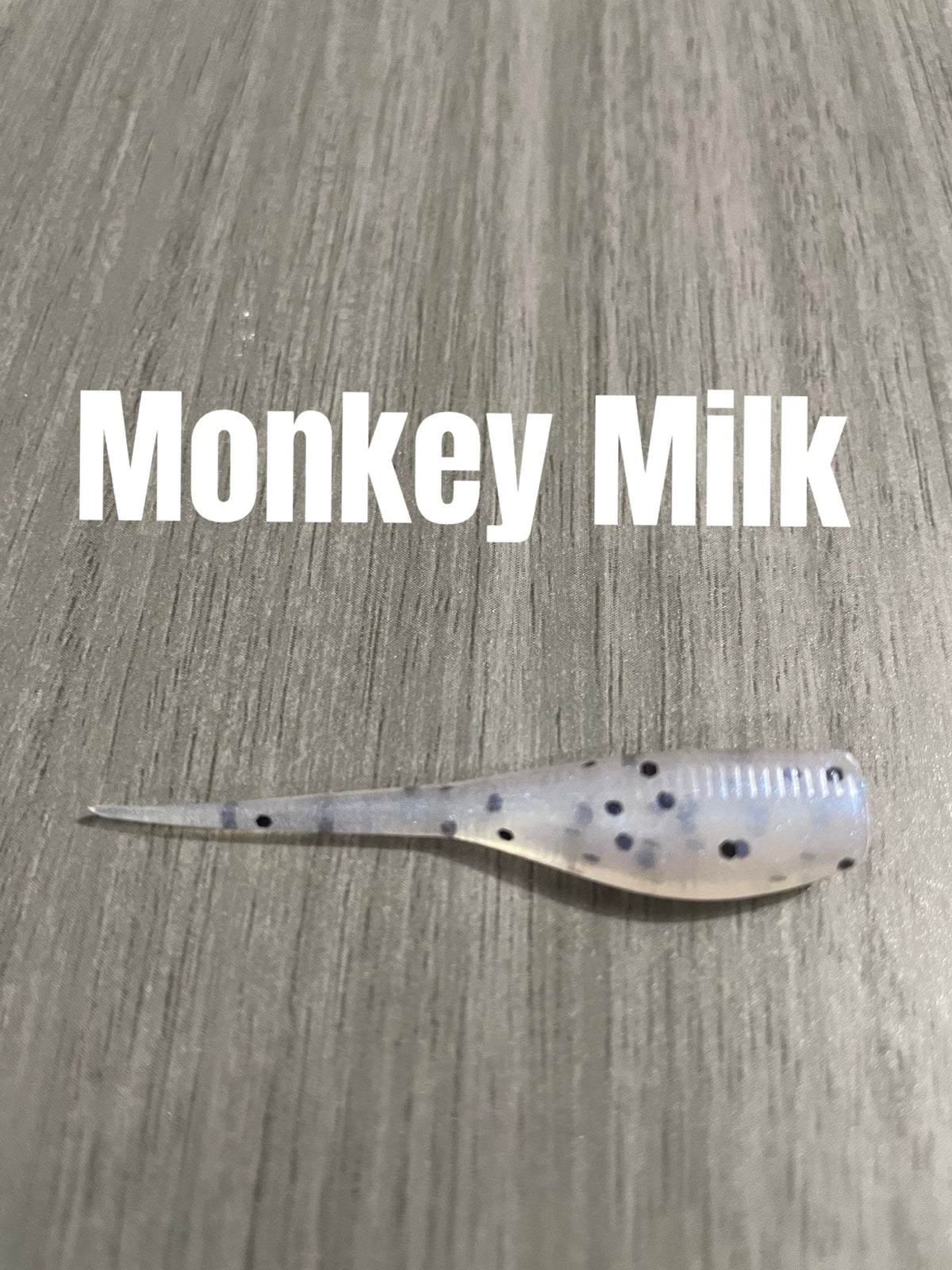 Monkey Milk Shad Body crappie bait with translucent milky-white body, dark blue-black speckles, and clear pointed tail.